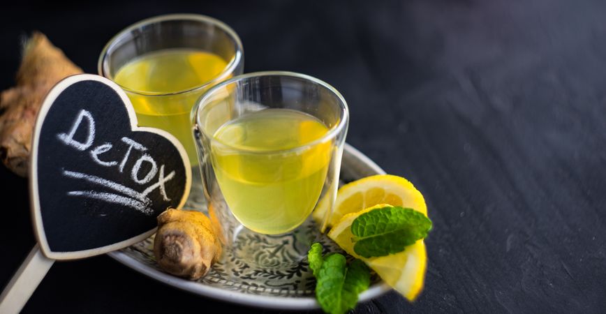 Two yellow detox drinks with ginger and lemon
