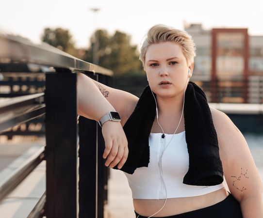 Serious woman in fitness gear leaning on rooftop rail