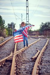 Kid smiling with USA national flag on rails