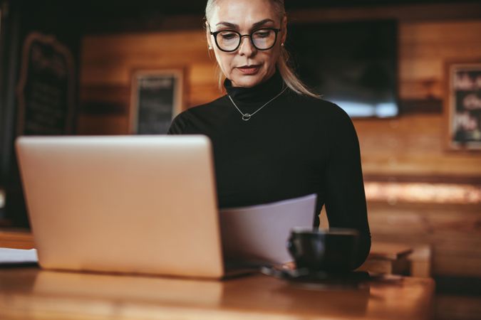 Mature businesswoman reading some documents at coffee shop