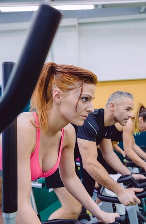 Line of people on stationary bikes working out in a gym