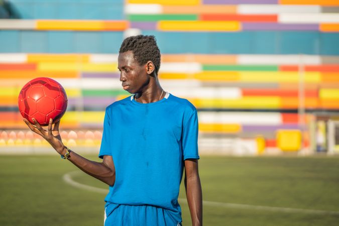 Black teenager with football ball against sky