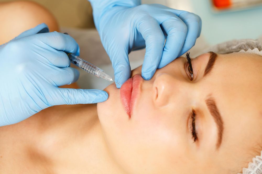 Hands in latex gloves performing injectable beauty treatment for client