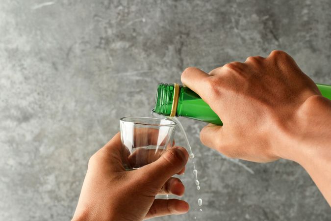 Hands pouring soju into glass