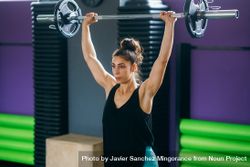 Sporty woman lifting barbell overhead in gym 5Xv6kb