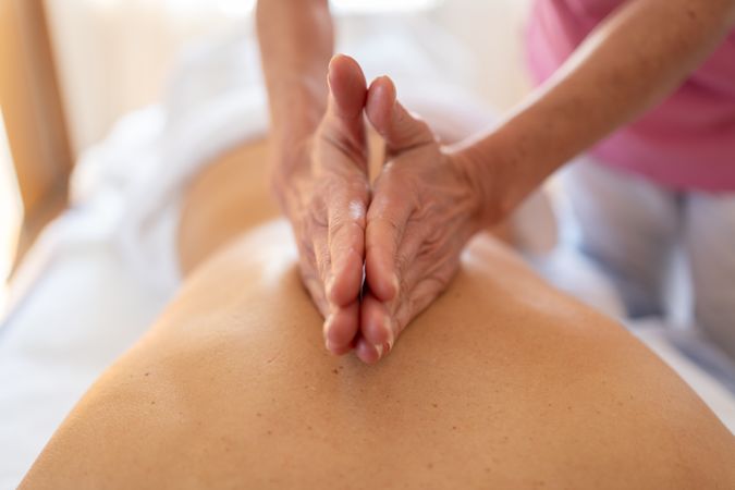 Close up of hands of physical therapist working on client's back