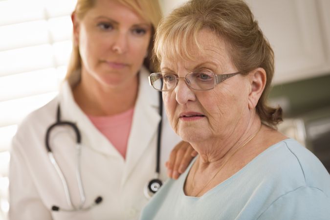 Older Adult Woman Being Consoled by Female Doctor or Nurse