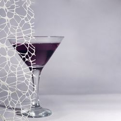 Dark cocktail in martini glass behind lace