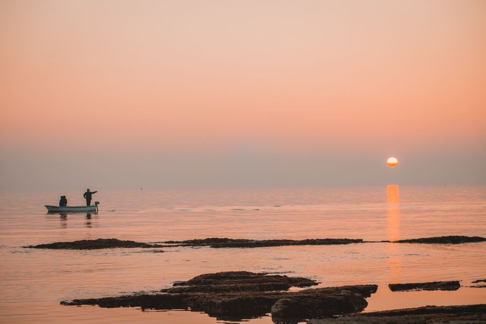 Silhouette of person in motor boat beach during sunset