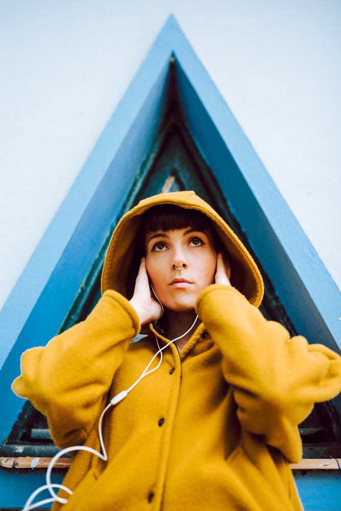 Cheerful female near triangle window listening to the music