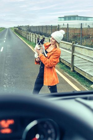 Looking out of van window at women holding cute dog, vertical
