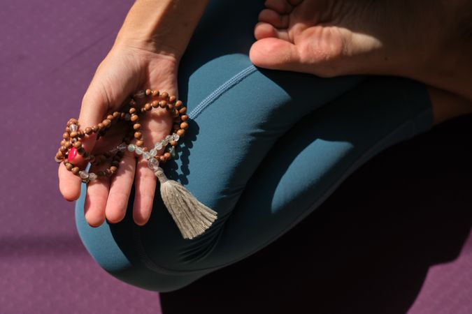 Flexible woman with beads doing yoga in Lotus pose