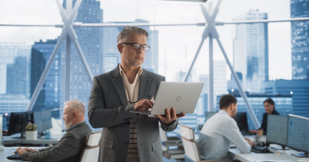 Male Entrepreneur Using Laptop Computer In E-commerce Company Workspace.