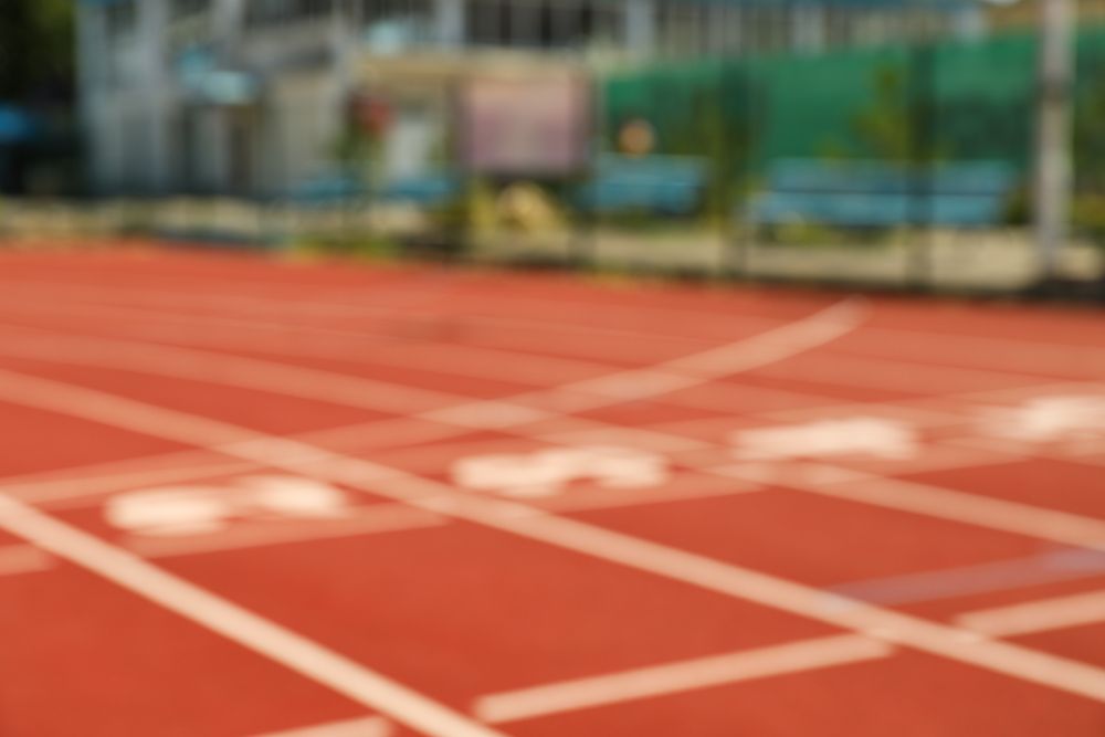 Start of red athletic track with numbers, blurred background