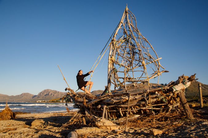 Young woman on decorative wooden ship near water on shore