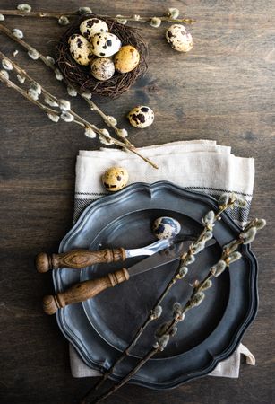 Top view of Easter table setting with quail eggs in nest and pussy willow