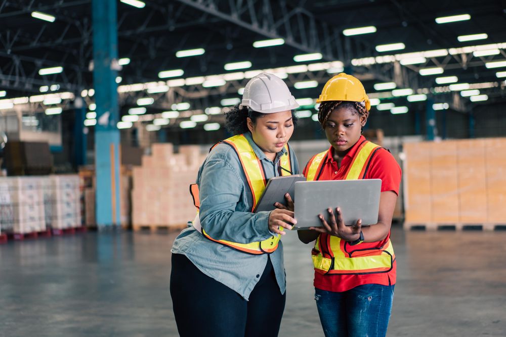 Female co workers discussing work together in distribution center