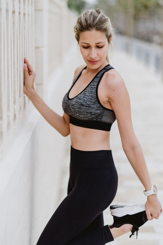 Sportswoman in sports clothing doing workouts at city street