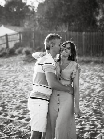 Laughing couple hugging on sandy beach
