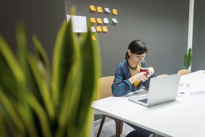 Businesswoman with hot beverage using laptop