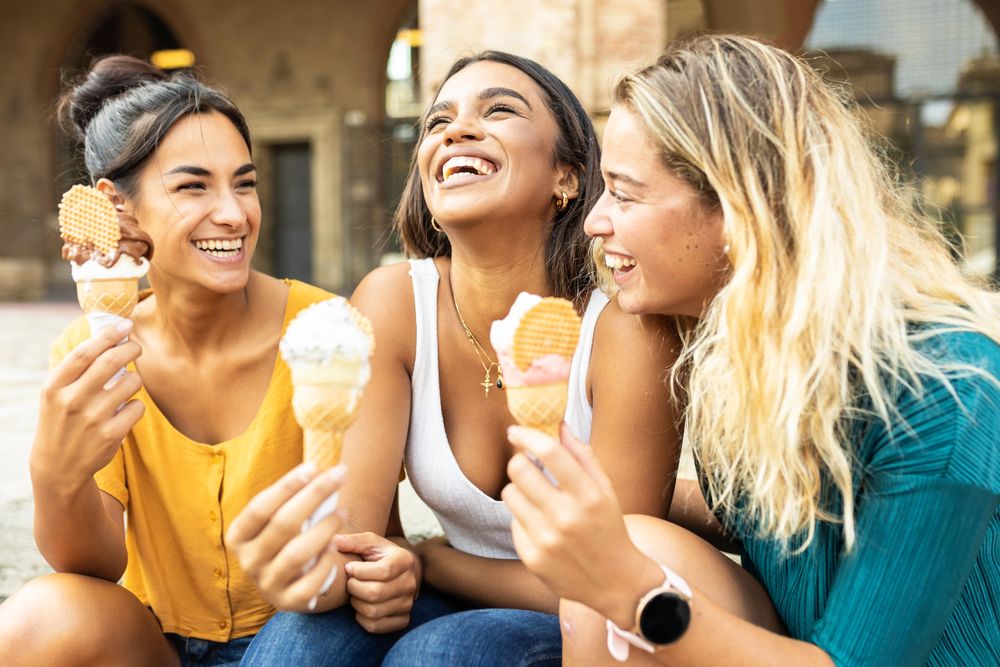 Three cheerful multi-ethnic women eating ice cream in Italy