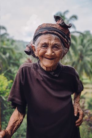 Portrait of older woman standing outdoors and smiling at camera in Bali
