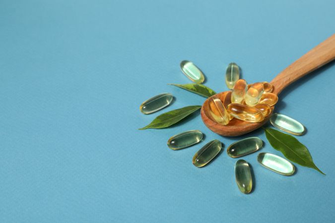Wooden spoon with omega pills and leaves
