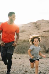 Black man jogging with toddler on nature