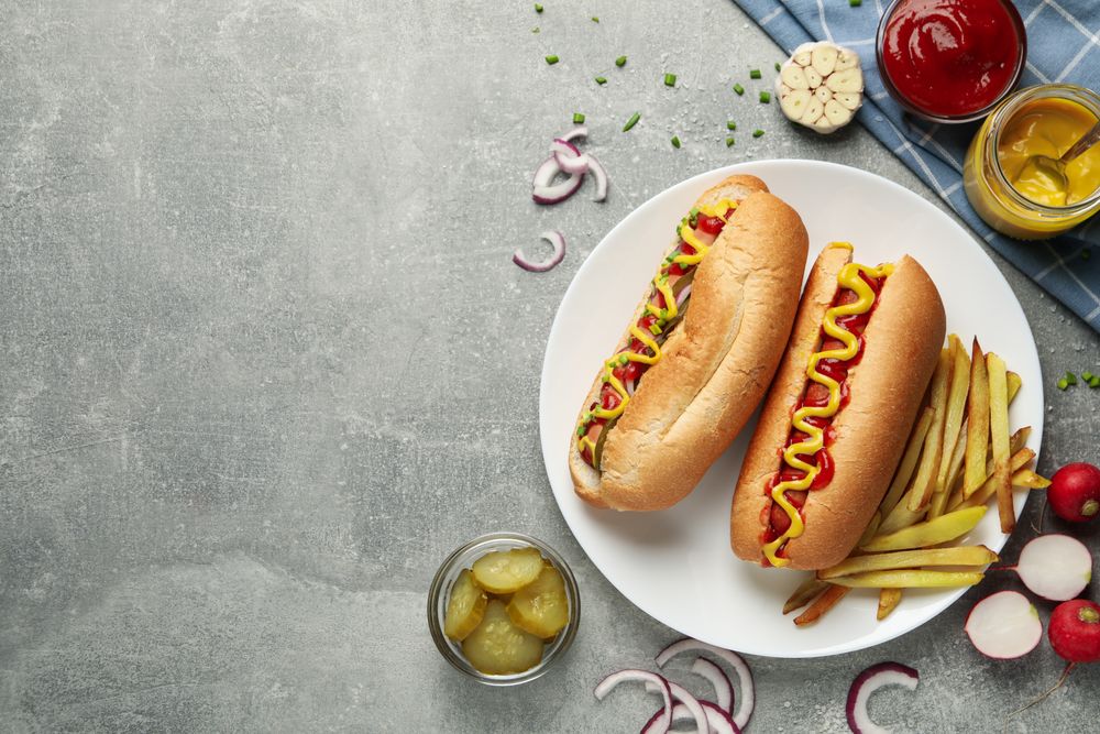 Tasty hot dogs and fries potato on gray table, top view