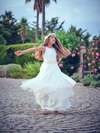 Cheerful child spinning around on pavement in park