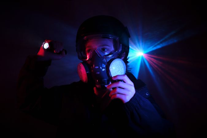 Thief in respirator in dark studio with neon lights