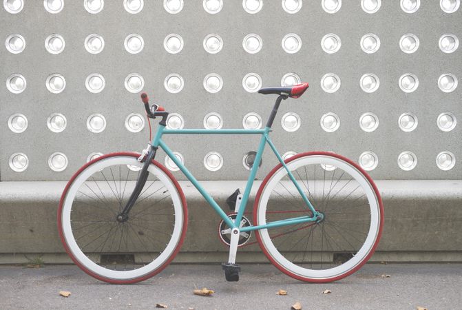 Red and green bike parked in front of patterned cement wall