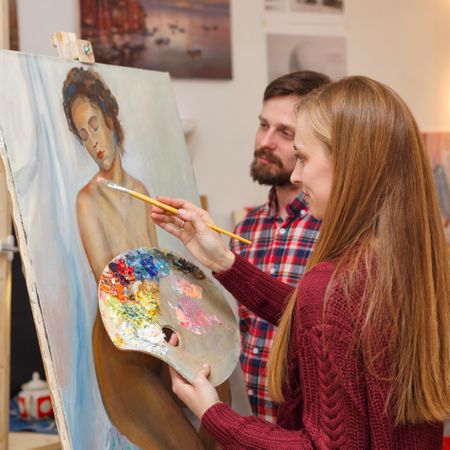 Male observes female painting a nude