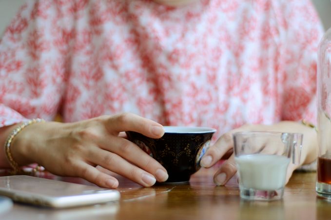 Cropped image of person holding dark ceramic cup