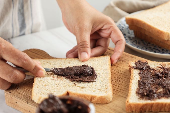 Spreading Chocolate Hazelnut Butter on Slided Bread.