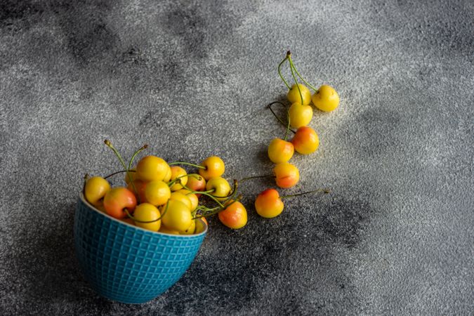 Yellow cherries spilling out of blue bowl