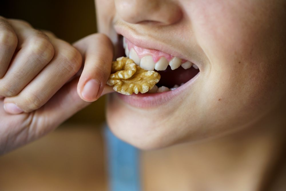 Crop unrecognizable teenage girl eating healthy walnut