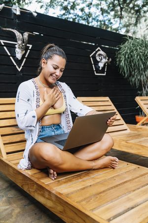 Relaxed woman using laptop while resting on deck chair