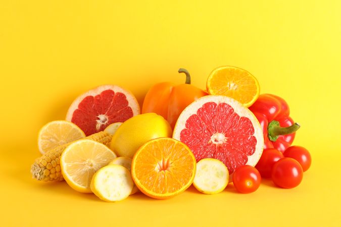 Different vegetables and fruits on yellow background, copy space