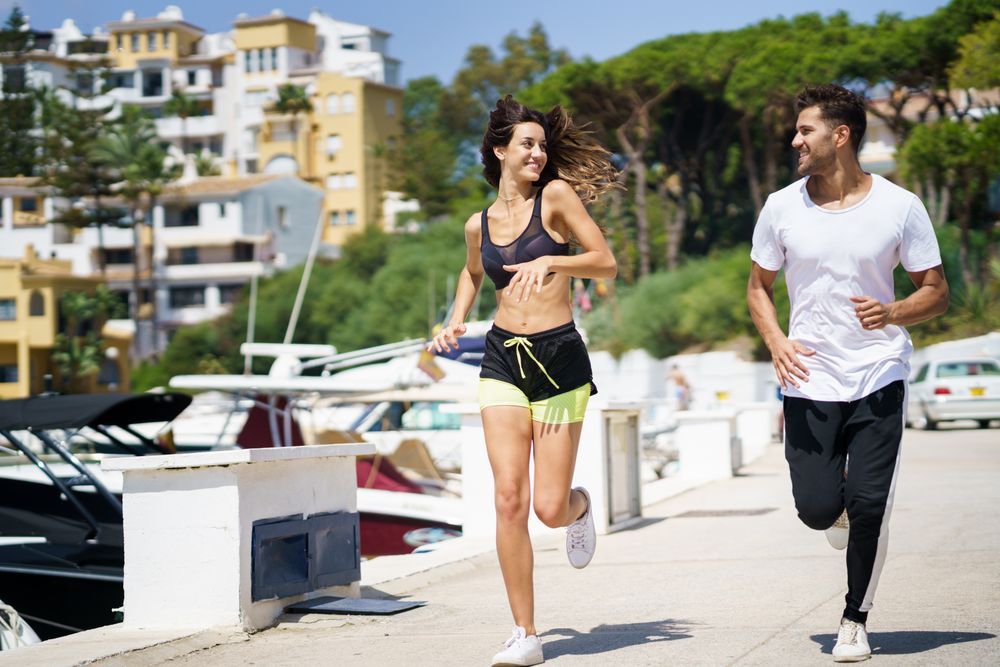 Happy man and woman jogging outside on pier