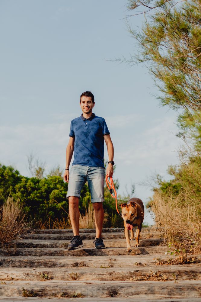 Happy adult man walking with dog along rural pathway