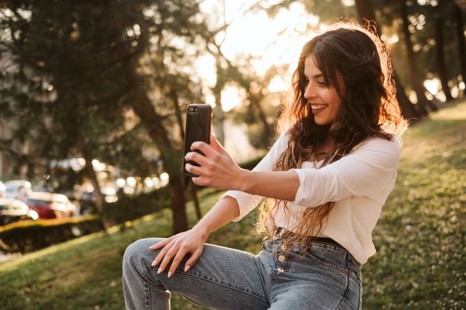 Cheerful woman taking selfie in park
