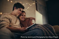 Couple sitting in cozy living room with a laptop 0JGAld