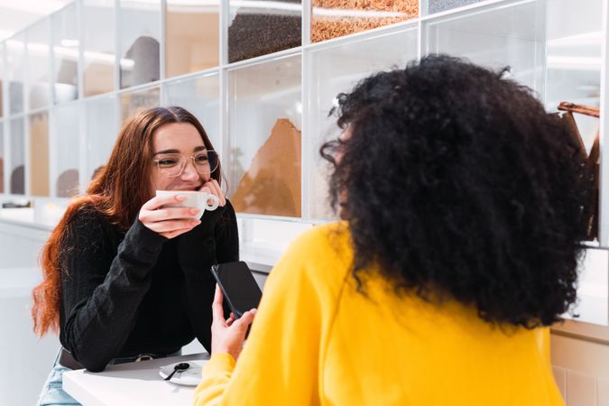 Happy young diverse women drinking coffee and talking in cafe