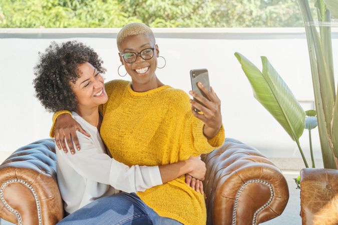 Cheerful diverse lesbian women hugging and taking selfie