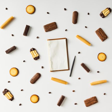 Notepad with cookies and coffee bean pattern on light background