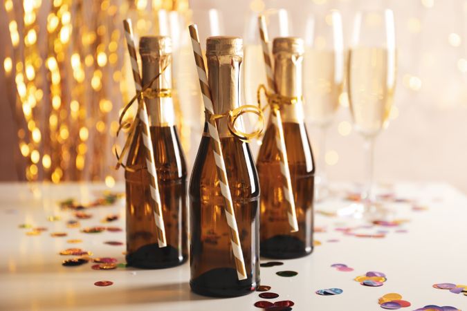 Champagne glasses and mini bottles on decorated background, space for text