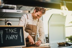 Young chef cooking inside vegan food truck restaurant - Focus on face