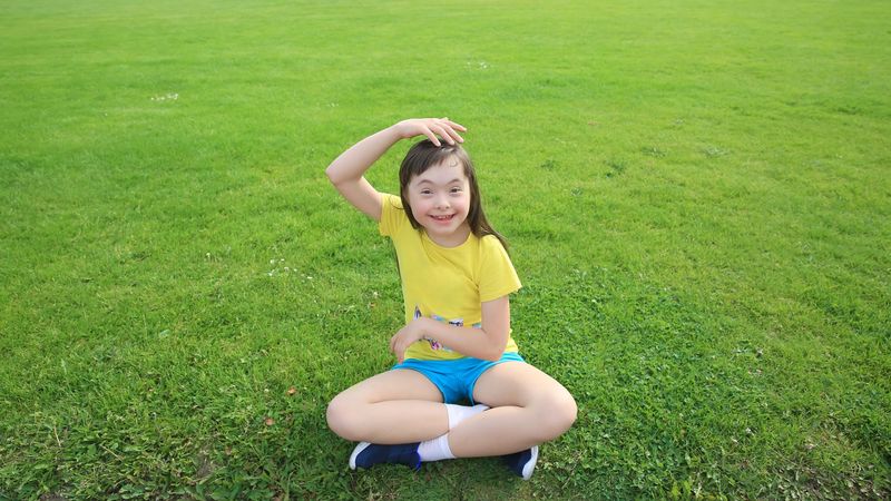 Playful child being silly and sitting on grass