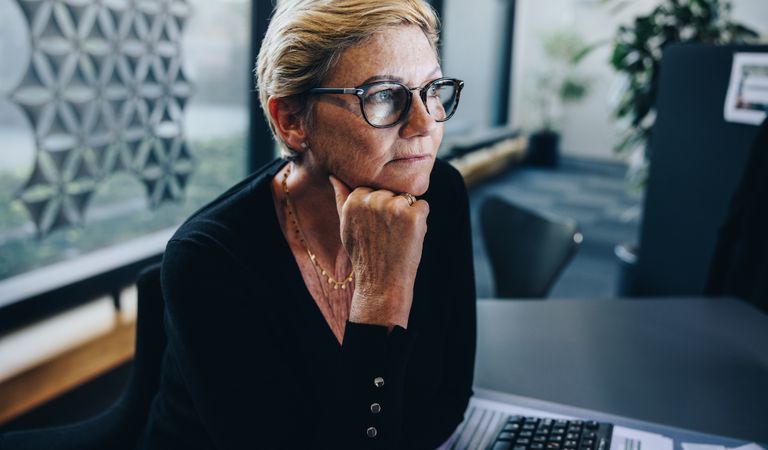 Mature woman in deep thought as she sits at her office desk